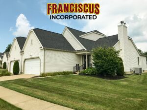 white home with mowed grass and Franciscus Roofing logo